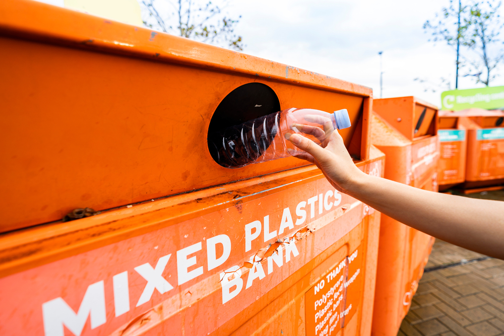 Recycling a plastic bottle at a bottle bank, The deposit return scheme is set to cost retailers £18.8 billion a year from 2025, ten times the amount officials previously claimed.
